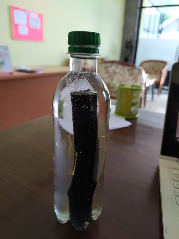 A binchotan charcoal stick standing in a bottle of drinking water